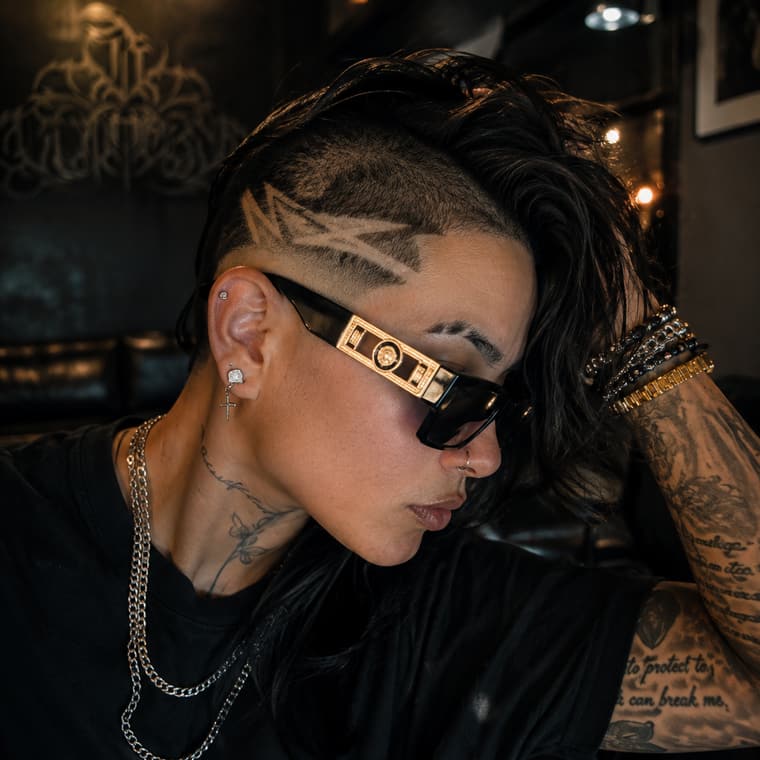 Long textured cut with a shaved side pattern, styled back.