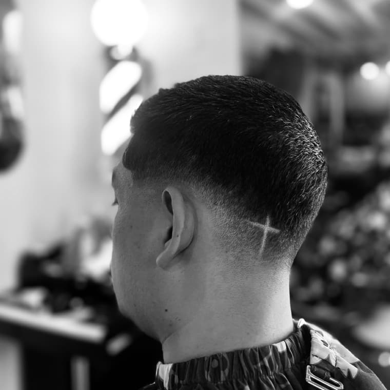 Close crop with a skin fade and a cross detail shaved at the temple.